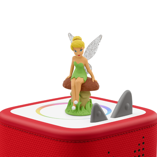 Tonies Audio Character - Tinker Bell figurine in a green dress with translucent wings sitting on a brown mushroom with green grass base, placed on a red Toniebox audio player with white top and grey control ears, designed for screen-free educational play for kids.