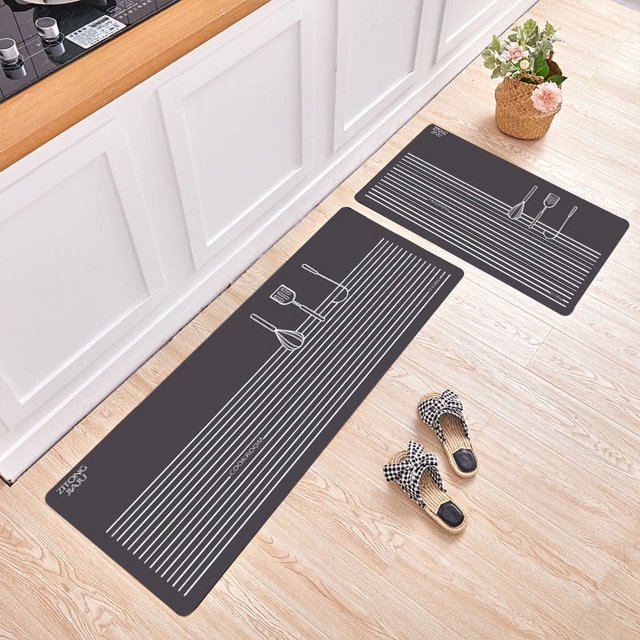 Ruidigrace 2Pcs/Set Nonslip Floor Mat Oil Absorbent Long Kitchen Carpet Rug for Home Kitchen. Two rectangular mats with a dark grey base and white line patterns featuring kitchen utensils, placed on a light wood floor near a kitchen counter. Ideal for kitchen decor, sizes are 40x60cm and 40x120cm, made of polyester with a flannel texture and anti-slip backing.
