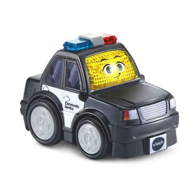 VTech Go! Go! Smart Wheels® Voiture de Police Utile Voiture Jouet pour Enfants en Vue avant 3/4, avec une Carrosserie en Plastique Noire et Blanche avec Texte « Service Communautaire », un Visage Souriant Jaune sur le Pare-Brise, une Barre Lumineuse Rouge et Bleue sur le Dessus et des Roues Grises, Conçue pour le Jeu Interactif des Tout-Petits et le Développement des Habiletés Motrices.