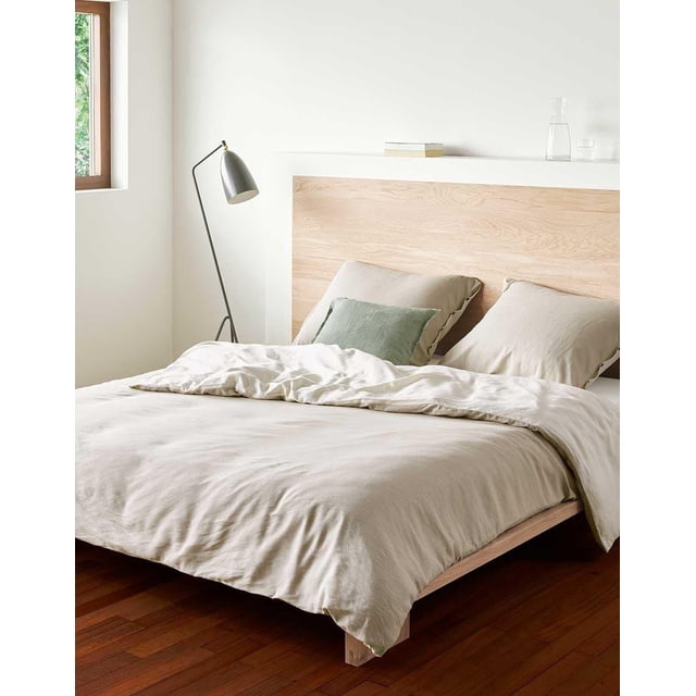 Essenza Home Duvet Cover Bedding Set on a queen bed featuring a light beige percale cotton duvet cover and matching pillow shams, accented with a green pillow, set against a natural wood headboard in a bright room with hardwood floors and a black floor lamp by a window, suitable for enhancing bedroom comfort and style.