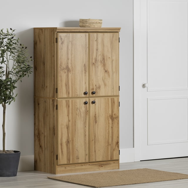 South Shore Morgan Armoire de Rangement à 4 Portes en Chêne Nordik, Vue de devant Montrant une Armoire Haute en Bois avec Quatre Portes et Poignées Rondes Noires Regroupées au Centre, Fini grain de Bois Chêne Naturel avec Bord Supérieur Texturé, Placée sur un Plancher de Bois Franc Clair à Côté d'Une Plante en Pot et d'Une Porte à Panneaux Blancs, Offrant un Rangement Polyvalent pour l'Entrée avec des Tablettes Ajustables pour Organiser les Articles Ménagers.
