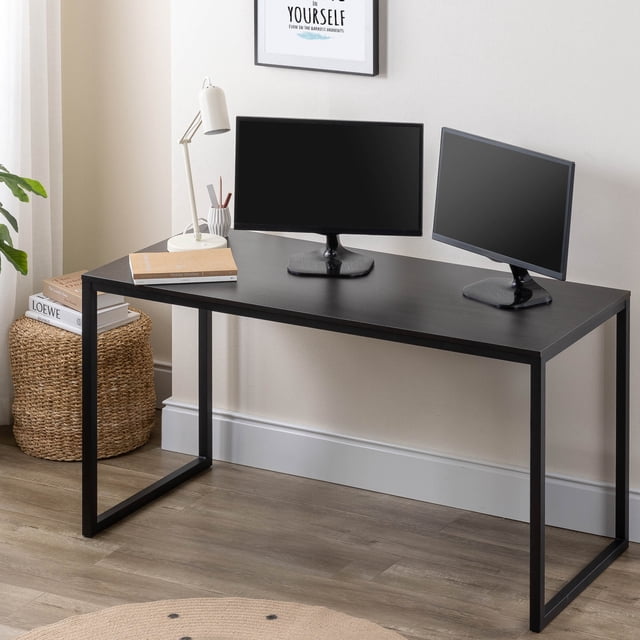 Zinus Jennifer 55 inch computer office desk with a black rectangular tabletop and black metal frame legs, shown with two black monitors, a white desk lamp, and books, set against light beige walls and wood flooring, ideal as a modern minimalist multipurpose table for home or office.