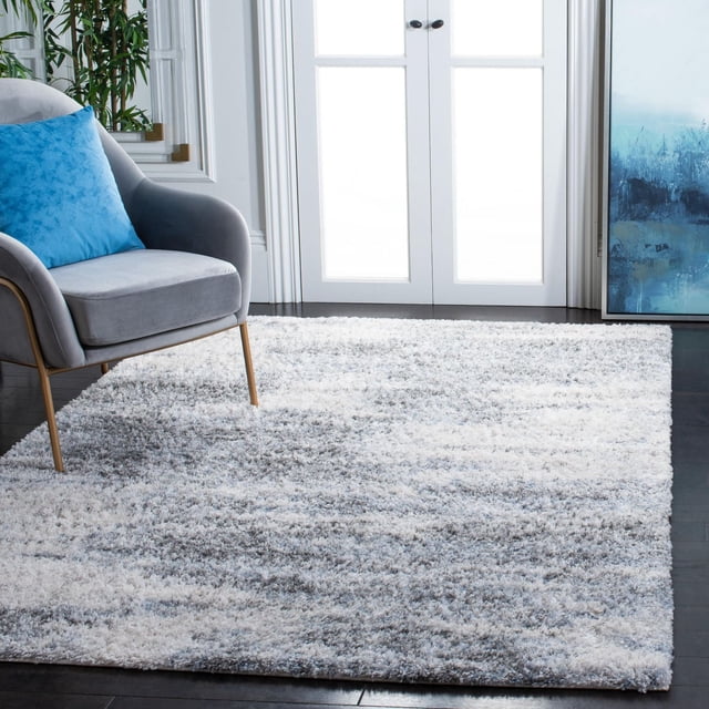 SAFAVIEH Berber Kyler Tapis Shag Abstrait avec Poil Shag Bas et Doux en Motif tribal Abstrait Gris et Blanc, Tissé Mécaniquement pour un Entretien Facile et une Durabilité, Exposé sur un Plancher de Bois Franc Foncé à Côté d'Un Fauteuil Gris avec un Coussin Bleu et des Portes Françaises Blanches, Convient pour Ajouter Chaleur et texture aux Zones de Tapis d'Accent.