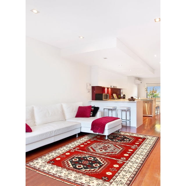 ECARPETGALLERY 100% Wool Traditional Indoor Area Rug with bold geometric Kazak patterns in red, black, and cream tones, placed on hardwood floor in a modern living room with white sectional sofa accented by red pillows and throw, adjacent to a white kitchen with stainless steel appliances and bar stools, suitable for entrance, bedroom, living room, or dining room use.