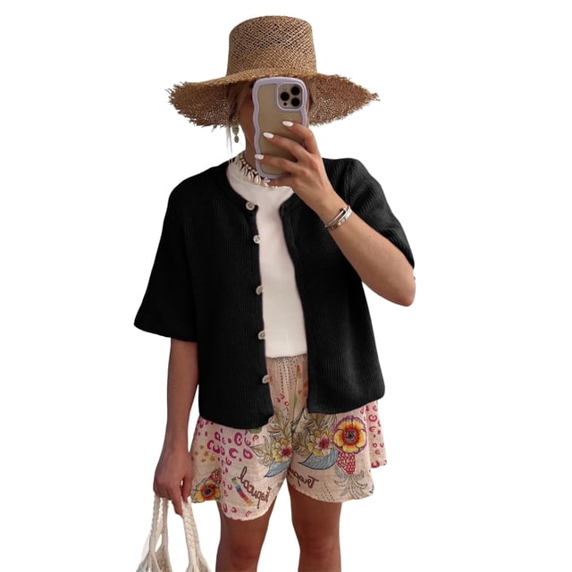 Gupgi Knitted Crop Cardigan for Women, a short sleeve button-down sweater in solid black ribbed knitwear. Features a round neck and lightweight design, styled with floral shorts, a white inner top, and a straw hat. Ideal for casual outings, summer wear, or layering.