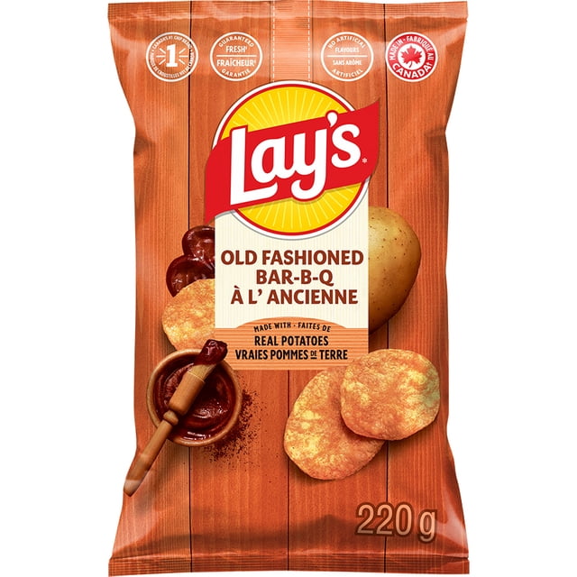 Lay's Old Fashioned Bar-B-Q flavoured Potato Chips 220 g bag with wood panel background, featuring Lay's logo, crispy potato chips, a whole potato, and barbecue sauce with a brush, made with real potatoes and no artificial flavours, made in Canada, suitable for casual snacking.
