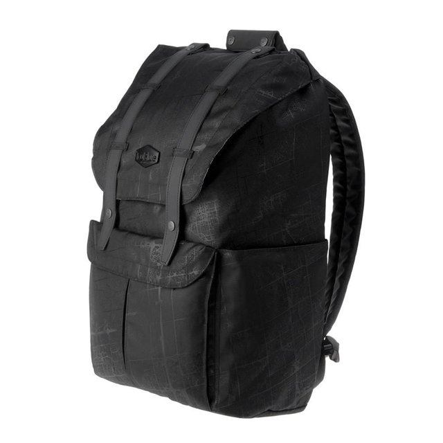 TruBlue The Patriot Backpack 21L in black with subtle map pattern, flap top secured by leather straps with snap buttons, padded adjustable shoulder straps, side pockets, and water-repellent polyester construction for organized daily use.