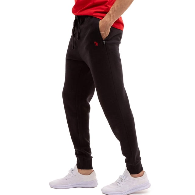U.S. Polo Assn Jogger en Molleton Noir avec Taille Élastique, Cordon de Serrage, Poches Latérales Zippées, Poignets Côtelés aux Chevilles et logo Brodé Rouge sur la Cuisse Gauche, Convient aux Tenues Décontractées Ou aux Entraînements Légers Assorti à des Espadrilles Blanches et à un Chandail Rouge.