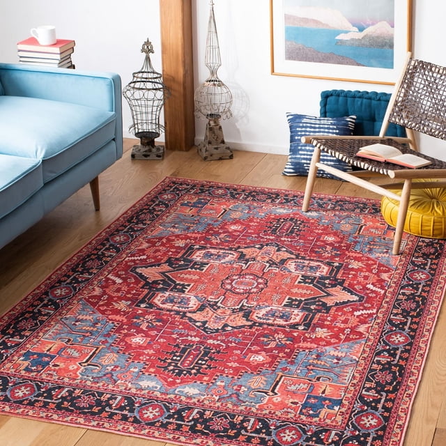SAFAVIEH Serapi Glenn Oriental Area Rug with a red and blue central medallion and floral design, power loomed from cotton, viscose, and polyester in a soft close cut pile, displayed on light wood flooring in a living room with a light blue sofa, woven chair with an open book, decorative pillows, and framed wall art, ideal for adding a traditional yet contemporary accent to home interiors.