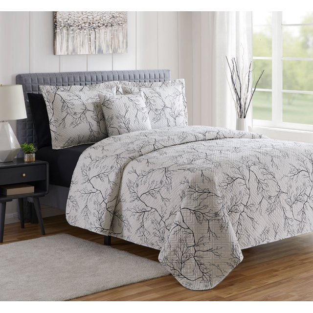 Clara Clark Quilt Set, 7 Piece Quilt Bedspread Coverlet Bedding Set, King Quilt 96"x108", with a branch pattern in contrasting tones. The set includes a quilt, fitted sheet, pillowcases, pillow shams, and a Euro sham. Shown in a contemporary bedroom with a grey upholstered headboard, a nightstand, and ample natural light from a window.