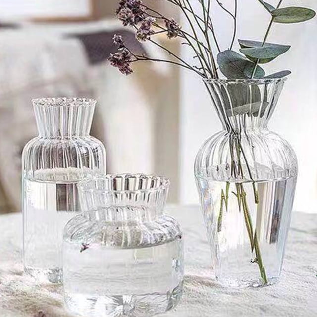 Simple Design Vase Versatile Home Decor Flower Vase Decorative Transparent Vase for Wedding. A collection of transparent glass vases with a striped design, available in various shapes and sizes. The vases are displayed on a table, filled with water and holding delicate floral stems. Ideal for decorative accents in living rooms, bedrooms, or offices.