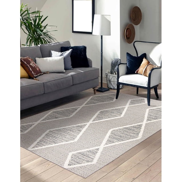 ECARPET Jute Style Area Rug for Bedroom, Living Room, Dining Room Specter Collection in a bright living room with light wood flooring, featuring a textured geometric diamond pattern in neutral tones on a dense, looped pile. Positioned between a gray sofa with cushions and a white armchair with dark frame and pillows, near a floor lamp and wall decor. Suitable as an accent rug to add rustic texture and warmth to home spaces.