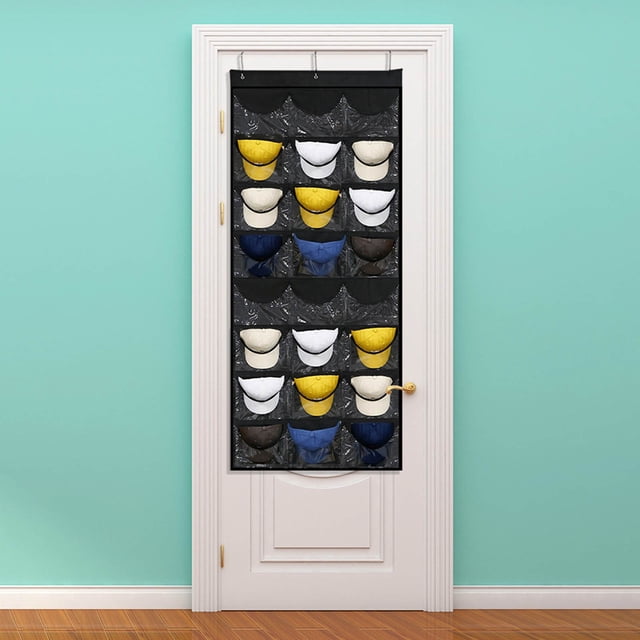 24-Pocket Baseball Hat Rack for Wall or Door Organization, featuring clear PVC pockets and three metal hooks for easy hanging. The black organizer measures 65x26 inches and is displayed hanging on a white door in a room with teal walls and wooden flooring. The rack holds various baseball caps in its transparent pockets, showcasing its capacity and organization.