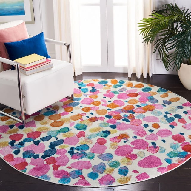 Safavieh Lillian Isadora Tapis à Pois Brossés, un Tapis d'Accent Rond à Poil Ras avec une base Blanche et des Points pastel Multicolores en Rose, orange, Bleu et Sarcelle. Exposé sur un Plancher de Bois Franc Foncé Près d'Un Fauteuil Blanc avec des Coussins Bleus et Roses et une Plante en Pot Verte par des Rideaux Transparents. Convient pour Ajouter une Couleur Vibrante et un style durable aux Intérieurs de la Maison.