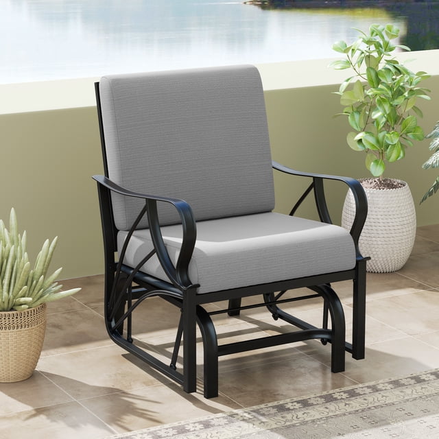 Gymax Patio Glider Chair Single Outdoor Rocking Chair in gray with seat and back cushions. Features a heavy-duty metal frame with curved armrests and a breathable fabric surface. Designed for smooth, noiseless gliding and ergonomic comfort. Shown on a tiled patio with potted plants and a view of water in the background.