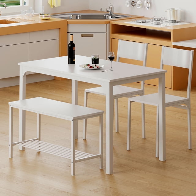 SOGES Dining Table Set of 4 in rustic white, featuring a 5-piece set with a rectangular table, 2 chairs, and 1 bench. The table measures 43.3 inches long, 27.6 inches wide, and 29.9 inches high. The chairs are 15 inches by 15 inches with a height of 34 inches, and the bench is 33.5 inches long, 14.2 inches wide, and 18.3 inches high. Made with durable E1 class wood and a heavy-duty powder-coated metal frame, this set is waterproof, scratch-resistant, and easy to clean. The rounded corners add safety, and the compact design is ideal for small spaces like kitchens, dining rooms, or studio apartments. Shown in a modern kitchen setting with light wood flooring and orange cabinetry.