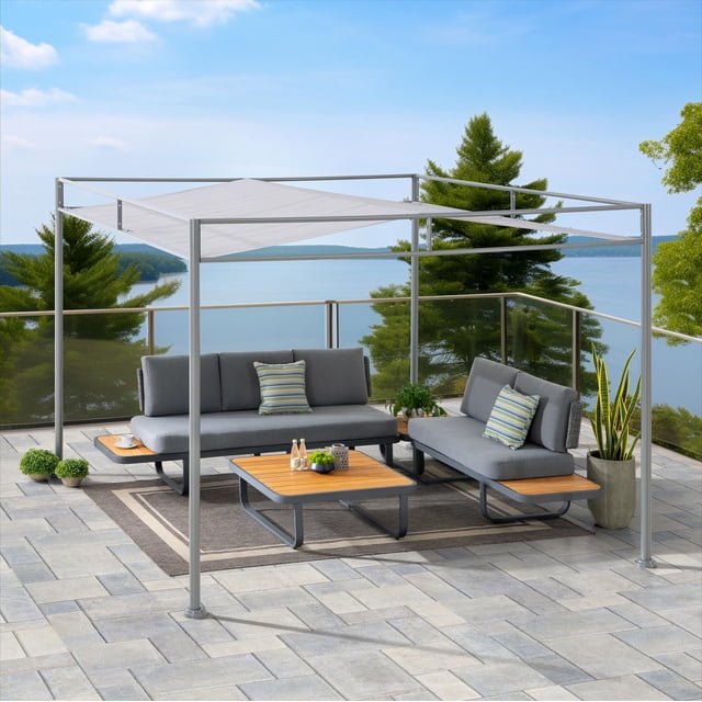 Sunjoy 10 ft. x 10 ft. pergola outdoor metal pergola gazebo canopy patio with a grey metal frame and light grey fabric canopy roof providing outdoor shade on a stone tile patio. Beneath are two grey cushioned sofas with striped pillows, wooden coffee and side tables, and potted plants, all overlooking a lake with glass railing. This durable pergola is ideal for backyard gatherings and outdoor relaxation.