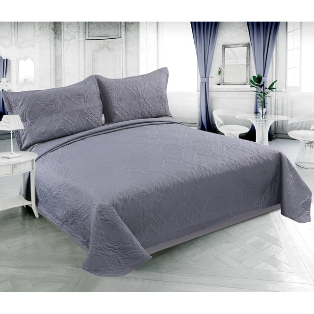 Marina Decoration Solid Embossed Pinsonic Coverlet Bedspread Bedding Ultra Soft Summer Quilt Set with Shams in grey, displayed on a bed in a bright room with white walls and blue curtains. The breathable, reversible quilt and matching pillow shams feature a solid grey color with embossed floral patterns, made from 100% brushed microfiber and polyester fill, suitable for all-season lightweight comfort.