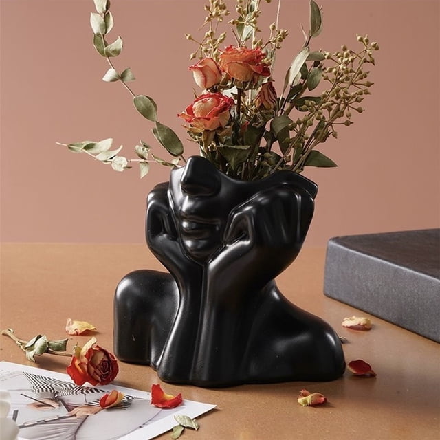 EGNMCR Resin Vase Stationery Pen Container crafted from black resin, featuring a sculptural face design with hands. Ideal for home office desktop decoration or as a modern decorative accent. Measuring 12x11x8cm, it is displayed on a wooden surface with dried flowers arranged inside, enhancing contemporary decor.