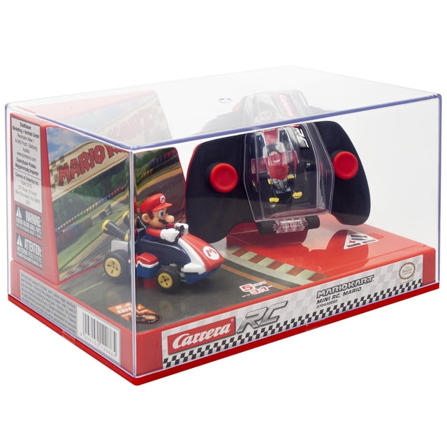 Nintendo Carrera RC - 2,4 GHz Mario Kart(TM) Mini RC, Mario dans un Emballage Transparent Montrant une Voiture Télécommandée Mario Kart Mini à l'Échelle 1:50 Rouge et Bleue avec Figurine Mario Assise, aux Côté d'Une Télécommande Noire avec joysticks Rouges et un Compartiment de Rangement Clair, Affichée sur une base à Thème de Piste de Course.