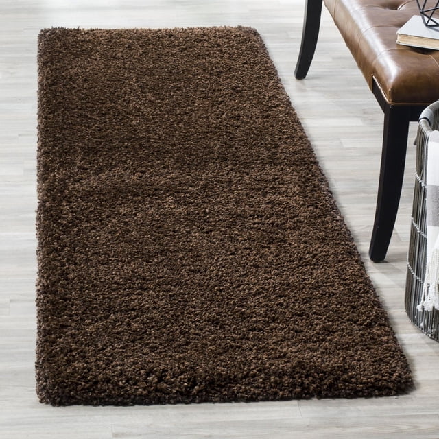 Safavieh California Tapis Shag Uni en Peluche Brun Foncé avec un Empilage de Polypropylène super dense de 4,5 Kg/m2, Exposé sur Plancher de Bois Clair à Côté d'Un Banc en Cuir Brun et d'Un Panier en Métal avec un Jeté, Présentant une texture Pelucheuse et un style Décontracté de la Côte Ouest Idéal pour les Zones d'Accent dans les Maisons.