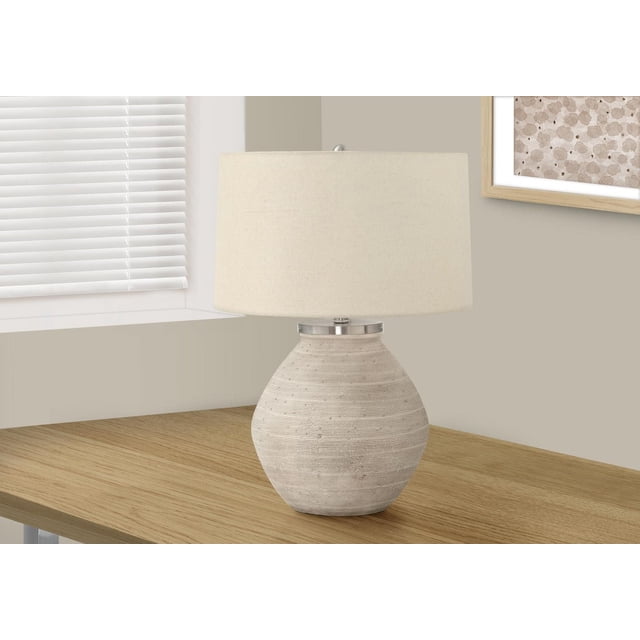Monarch Specialties Lighting 25"h contemporary table lamp with a cream concrete jar-shaped base featuring fine lined ridges, beige linen drum shade, and round silver finial, placed on a wooden table near a window with white blinds and framed abstract art, ideal for adjustable ambient lighting with a 3-way switch.