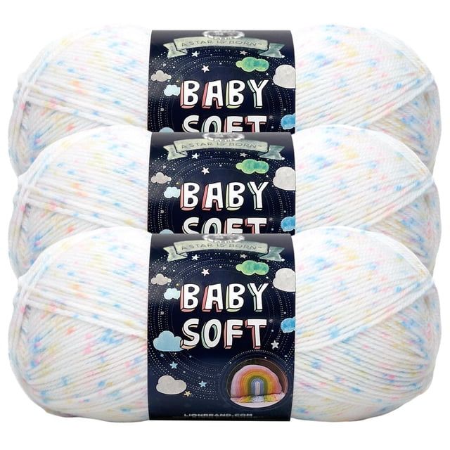 Lion Brand Baby Soft Yarn three 5 oz skeins stacked, white with pastel blue, pink, and yellow speckles, wrapped in a black label with stars and clouds, a soft acrylic blend ideal for knitting and crocheting baby blankets and clothes, machine washable for easy care.