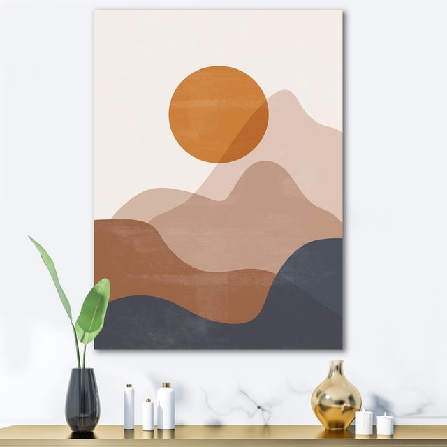Designart Abstract Red Moon In Earth Toned Mountains II Canvas Wall Art depicting layered abstract mountains in beige, brown, and dark blue with a burnt orange circular moon, printed on premium cotton canvas with gallery-wrapped edges, ready to hang above a modern console with decorative vases and a plant.