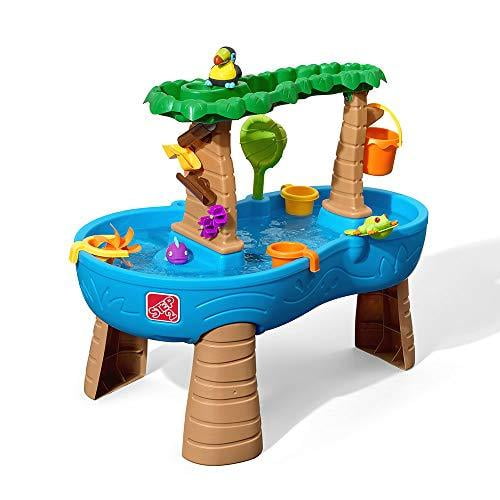 Step2 Tropical Rainforest Water Table in green and blue, featuring a tropical-themed design with a treetop canopy, maze-like spinners, ramps, and buckets. Includes a 13-piece accessory set with a tree-frog, toucan, and tropical fish. Designed for outdoor water play, it allows kids to pour water into the treetop basin for a rain shower effect and create waterfalls for STEM play. Suitable for multiple children to play together.