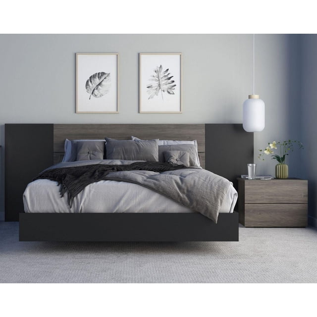Sinatra 4 Piece Bedroom Set, Bark Grey and Black, front view of a modern twin bed with a floating design, bark grey wood plank headboard with black side panels, and matching 2-drawer nightstand with a glass, books, and a small flower vase, set in a minimalist bedroom with light grey walls, carpeted floor, two framed monochrome leaf prints above the bed, and a white pendant light.