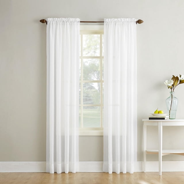 SUN TEXTILE CRUSHED ROD POCKET CURTAIN in white crushed sheer voile fabric hanging on a wooden rod over a window, softly filtering light while enhancing privacy, displayed in a neutral room with light hardwood floors and a white side table with a glass vase and books, ideal for layering to control light.