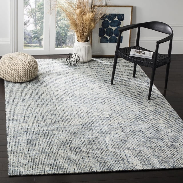 SAFAVIEH Tapis en Laine à Rayures Géométriques Delia Abstraites pour un Espace de Vie Contemporain avec des Planchers de Bois Franc Sombres, Présentant un Velours Doux en Laine pure Tufté à la Main en Boucle dans un Motif Géométrique Bleu et Crème, Style avec une Chaise Tissée Noire, un pouf Tricoté beige et un vase Blanc avec des Herbes Séchées Près des Portes en Verre, Convient pour Ajouter Chaleur et texture aux Intérieurs Modernes.