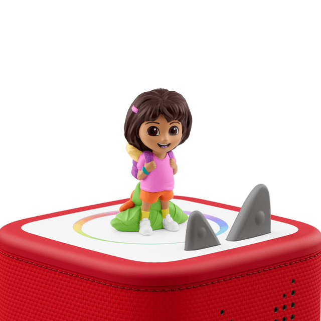tonies Dora the Explorer Figurine Audio Montrant un Personnage Peint à la Main avec des Cheveux Bruns, une Chemise Rose, des shorts orange, des Chaussures Blanches et un Sac à Dos Violet, Attachée Magnétiquement à un Lecteur Audio Toniebox Rouge avec une Toupie Blanche et un Motif Arc-en-Ciel Circulaire pour Raconter des Histoires Sans Écran.