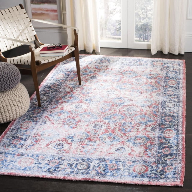 Safavieh Saffron Bronagh Tapis Oriental Vieilli pour Aire avec une texture en Coton Doux et un Motif floral Vieilli Coloré dans des Tons Rouge, Bleu et Crème, Posé sur un Plancher de Bois Franc Foncé Près d'Une Chaise Blanche Tissée et des poufs Tricotés dans une Pièce Éclairée par le Soleil avec des Rideaux Transparents, Idéal pour Ajouter Chaleur et style aux Intérieurs de la Maison.