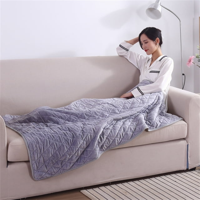 Birdeem Heated Blanket Soft 5V Safety Electric USB Blanket, shown in grey, measuring 75x120 cm (29.5x47.2 inches). Made of super soft polyester fiber, it features a quilted design and is draped over a person seated on a beige sofa. The blanket includes a built-in carbon fiber heating pad powered by USB, suitable for use with mobile power, laptops, or car USB adapters. Designed for home, travel, office, and outdoor use, it is machine washable and comes with a 120 cm extension line for added convenience.