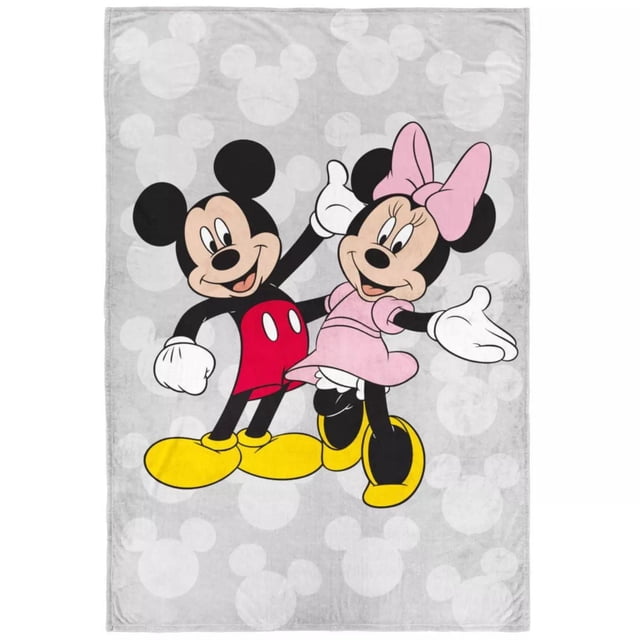 Minnie & Mickey Mouse Fleece Blanket in grey featuring subtle Mickey Mouse head silhouettes on the background and a large central print of Mickey in red shorts and yellow shoes with Minnie in a pink dress and bow, made of 100% polyester with a silky soft feel, machine washable and perfect for kids' bedrooms.