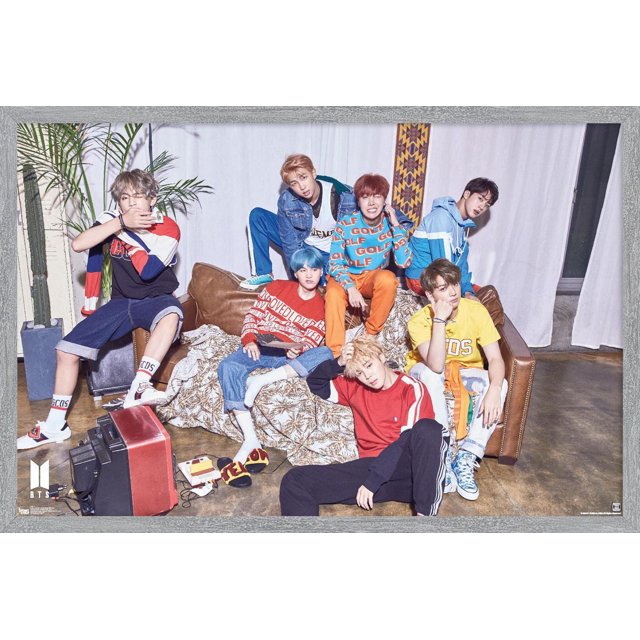 BTS - LOVE YOURSELF ? 'Her' Wall Poster, 22.375" x 34" framed showing seven BTS members in colorful casual streetwear posed around a brown leather couch with a patterned blanket, indoor plants, and vintage electronics on a polished concrete floor, suitable for bedroom or dorm wall art.