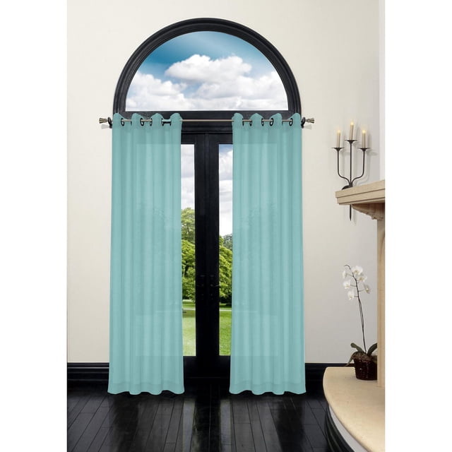 Safdie & Co. Curtain 86L Turquoise Bella Batiste with light-filtering turquoise fabric and grommet top, hanging on a black metal rod over a tall black-framed arched window and door in a modern room with dark hardwood floors, beige walls, a candle holder, and an orchid plant, suitable for layering or standalone use.