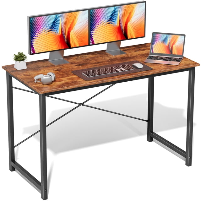 edx 47 inch Small Computer Writing Desk in rustic brown with a sturdy metal frame and crossbar support. The desk features a spacious particleboard surface, accommodating dual monitors, a laptop, and accessories like a keyboard, mouse, and headphones. Ideal for home offices, gaming, or studying, it is shown in a modern setup with a small potted plant for decor.