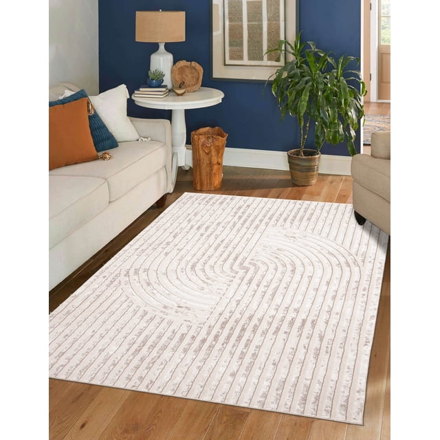 ECARPET Brie Contemporary/Modern Area Rug in beige and taupe with abstract geometric pattern, placed on hardwood floor in a living room with beige sofas, white round side table with lamp and decor, and a potted green plant by a navy blue wall. Suitable for living rooms, bedrooms, or hallways.