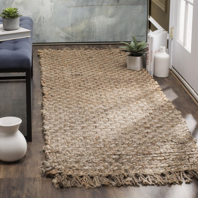 Safavieh Natural Fiber Eason Braided Area Rug in natural beige, crafted from durable braided sisal with fringed edges, placed on dark hardwood flooring near a white door, styled with a blue bench, white ceramic vases, and a small succulent, suitable for coastal and casual interiors and often used as a hallway runner.