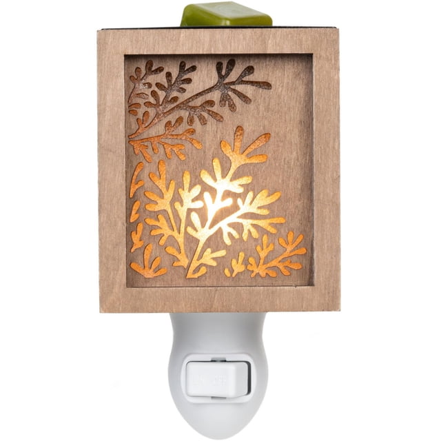 ScentSationals Accent™ Warmer - Evelyn with a wooden square frame featuring leaf-shaped cut-outs glowing softly from internal light, plugged into a white wall outlet with an on/off switch and a green wax melt cube on top, suitable for safe, flameless indoor fragrance and ambient lighting.