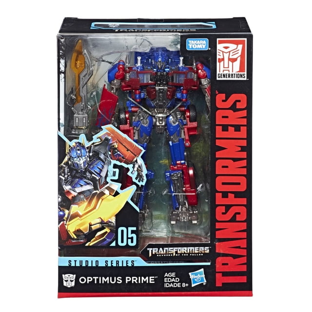 Transformers Série Studio 05 Classe Voyager Film 2 Optimus Prime Figurine en Emballage, Montrant un robot Détaillé de 6,5 Pouces avec Armure Bleue et Rouge, Pièces Mécaniques Argentées, et Deux Accessoires d'Armes Incluant une Lame Énergon, à l'Intérieur d'Une Boîte à Fenêtre Transparente avec Image de Marque Transformers Noire et Rouge et Graphiques de Film.