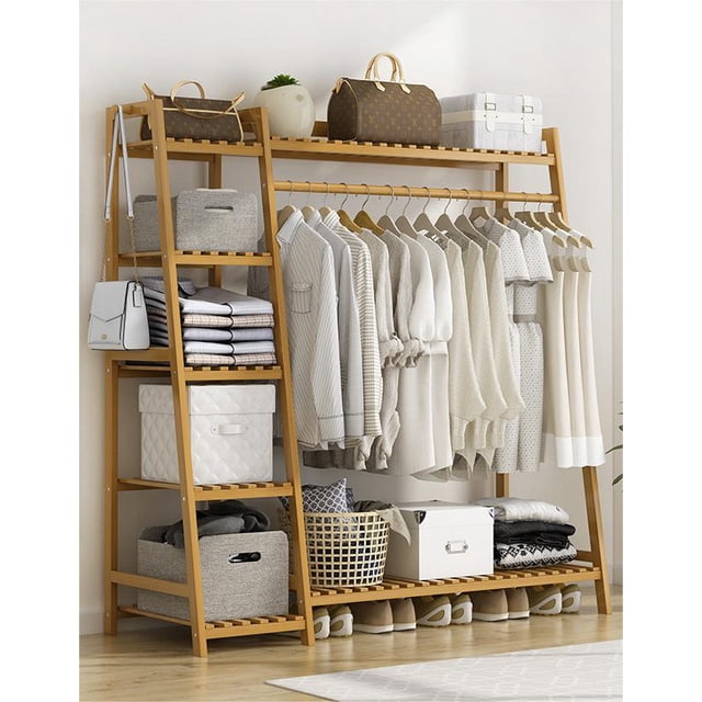 CC005 Storage Clothing Rack-Wood (130cm) made from sustainable bamboo in a natural wood finish. This closet organizer features a hanging rod for clothing, two lower shelves for shoes or storage boxes, and side shelving for folded items. It is displayed in a bright, organized room with various clothing and accessories neatly arranged, making it an ideal clothing storage solution.