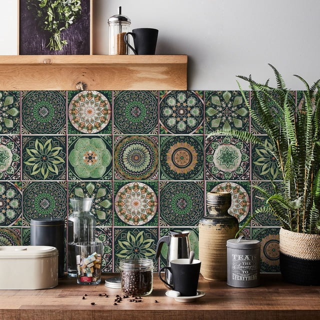 Lucoss 24pcs 6-inch peel and stick vinyl backsplash tiles featuring intricate, colourful patterns in green, orange, and white. The tiles are displayed in a kitchen setting, applied to the wall behind a wooden countertop with various decor items, including plants, jars, and a coffee maker. These removable, waterproof, self-adhesive decals are ideal for kitchen or bathroom decoration, suitable for renters, and perfect for spring Easter decoration.