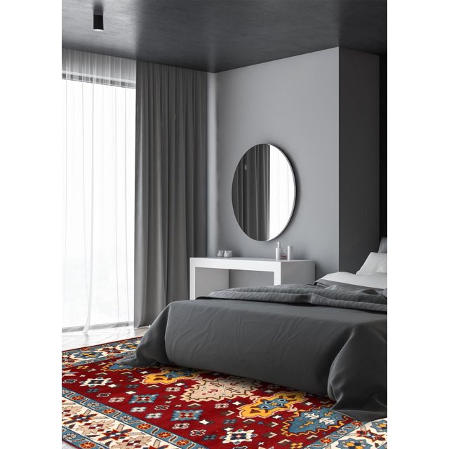 ECARPETGALLERY 100% Wool Traditional Indoor Area Rug for Entrance, Bedroom, Living Room and Dining Room with bold geometric Kazak patterns in red, yellow, blue, and cream tones, placed under a gray bed in a minimalist bedroom with gray walls, sheer curtains, a round mirror, and a white console table, often used to add warmth and style to indoor living spaces.