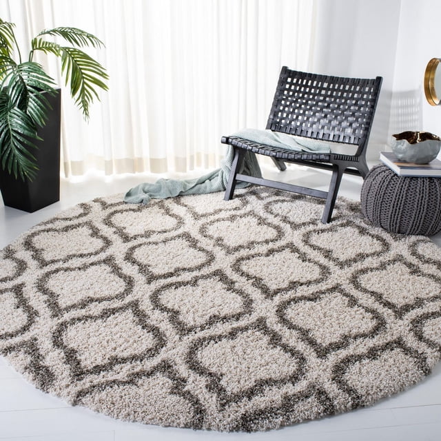 Safavieh Hudson Louise Tapis Shag Géométrique pour Aire, Rond avec Poil Shag Ivoire Pelucheux et Motifs de Carreaux Gris Foncé en Forme d'Oignon, Exposé dans une Pièce Éclatante avec des Rideaux Blancs, une Chaise Longue Tissée Noire Drapée avec un Jeté Bleu Pâle, un pouf Tricoté Gris et un Cache-Pot Noir avec des Feuilles de Palmier Vertes, Convient pour Rehausser la texture dans les Espaces de Vie Modernes.