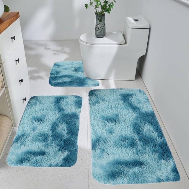 Czzoypi 3 Piece Bathroom Rug Set featuring a U-shaped contour rug, a rectangular mat, and a toilet lid cover in a mixed blue color. Crafted from soft microfiber shaggy material with velvet fleece and memory foam, these rugs are water absorbent, non-slip, and machine washable. The set is shown in a modern bathroom with the rugs arranged around a white toilet and on a tiled floor.
