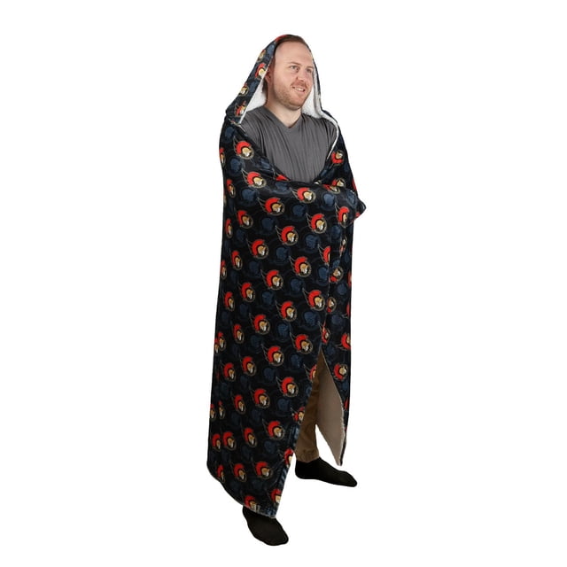 NHL Ottawa Senators Hooded Blanket, 50" x 70", worn by a standing person, featuring a black exterior with repeated Ottawa Senators logos in red and beige, sherpa-lined hood and interior, designed for warmth and comfort during indoor or outdoor use, also suitable for cozying up on summer nights by the fire.
