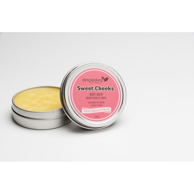 Sweet Cheeks Face and Body Balm in a small round silver metal tin with a pink label from Dimpleskins Naturals, showing lavender and vanilla scent and 30g weight, with the lid resting against the open container revealing smooth yellow balm inside on a white background, suitable for soothing chapped skin.